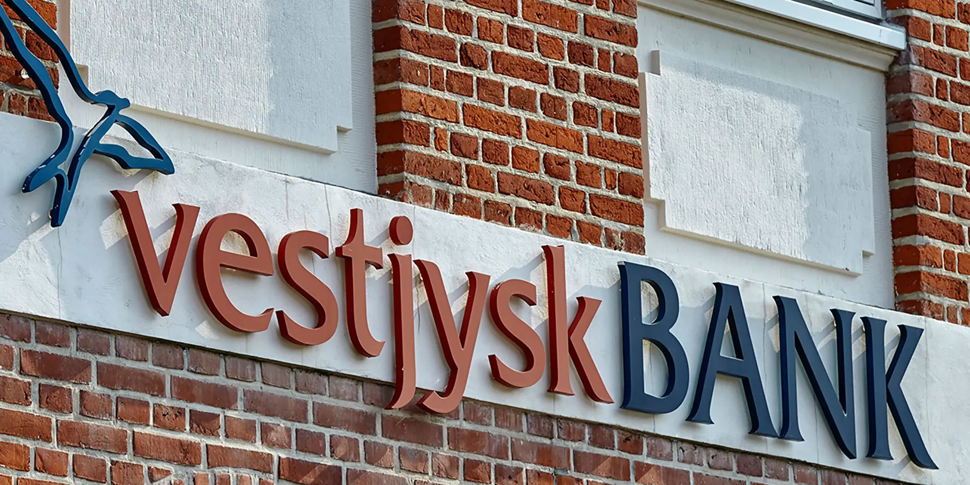 Facade på en bygning, hvor der hænger et logo fra Vestjysk Bank 